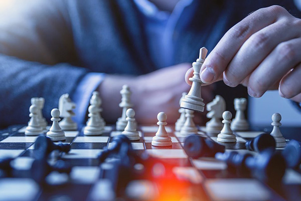 A closeup of a hand moving a chess piece on a board