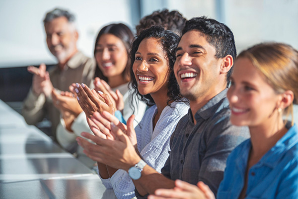 A row of people at a table clapping their hands