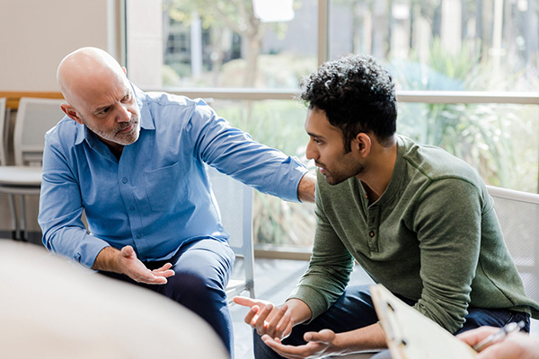 Two men in a conversation, one consoling the other