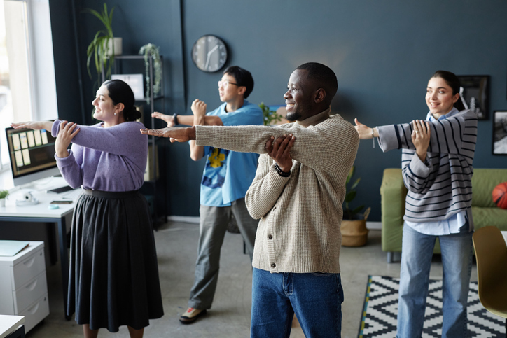 A group of office workers standing and stretching