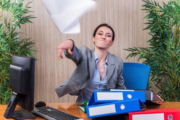 A woman behind a desk, throwing a piece of paper at the camera