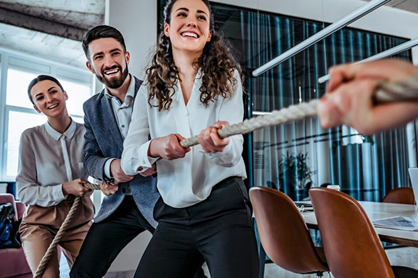 A group of people in an office environment playing tug of war