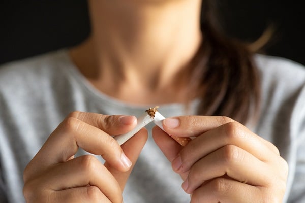 Woman breaking a cigarette in half with her hands