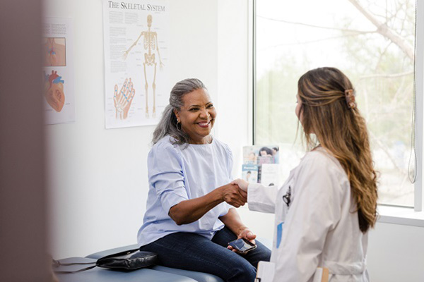 A woman in a doctor's office shaking hands with a doctor