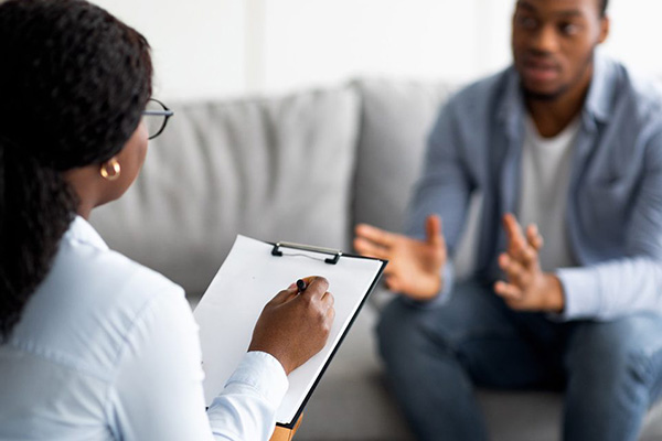 Two people in a conversation, one is writing down notes on a clipboard