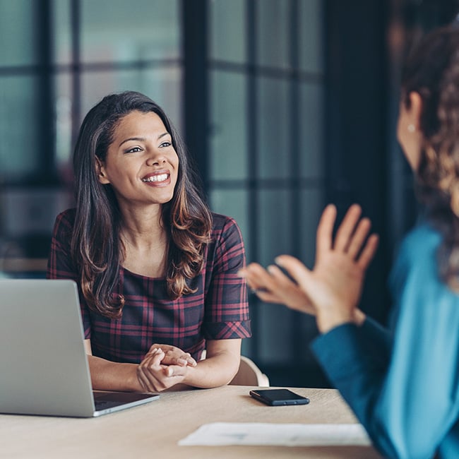 A woman with a laptop listening to someone else talking