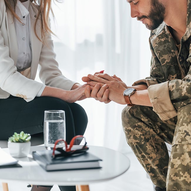 Two people holding hands, one in military fatigues