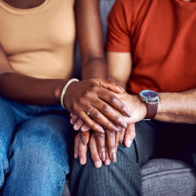 Two people overlapping hands on a knee