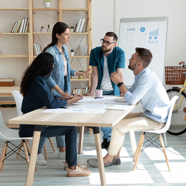 Four people gathered around a table talking about charts and graphs